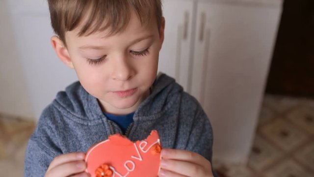 baby boy eating a gingerbread in the shape of a heart with the inscription love 