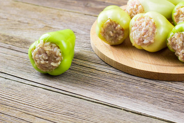 Raw peppers stuffed with meat on a wooden cutting board