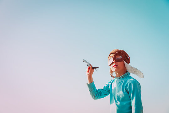 little boy with helmet and glasses play with toy plane on sky