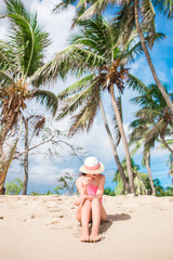 Young slim woman in bikini and straw hat on tropical beach. Beautiful girl under the palm tree on tropical Carlisle bay beach with white sand and turquoise ocean water at Antigua island in Caribbean