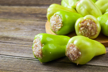 Raw peppers stuffed with meat on a wooden cutting board