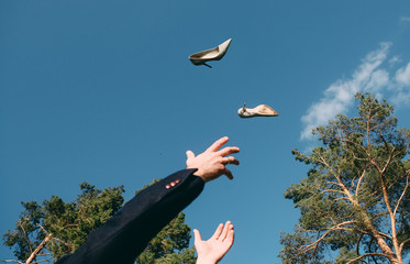 man throwing his shoes up catches his hands sky background