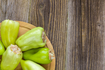 Raw peppers stuffed with meat on a wooden cutting board