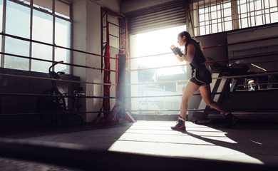 Fototapeta na wymiar Female boxer training inside a boxing ring