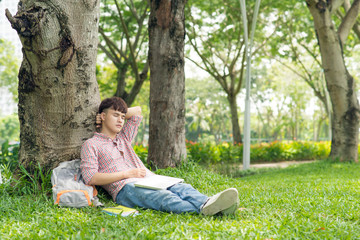 Young student, man relaxing smiling while lying on grass