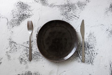 Black Plate on white wooden background with utensils