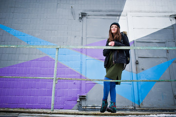 Young girl posed against colored wall in cold day.