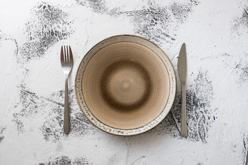 Plate on white wooden background with utensils