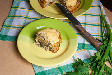 Piece of pancakes pie with mushrooms and chicken meat on green plate. Traditional meal for Maslenitsa - Russian pancake week..