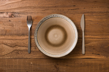 Plate on brown wooden background with utensils
