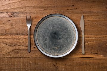Plate on brown wooden background with utensils