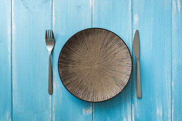 Plate on blue wooden background with utensils