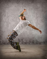 Fototapeta na wymiar Hip Hop dancer in dynamic action jump on the grunge grey backgro