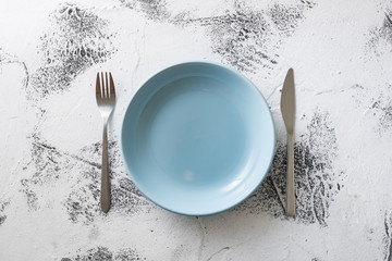 Blue Plate on white wooden background with utensils