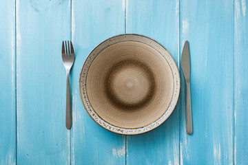 Plate on blue wooden background with utensils