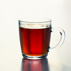 Glass cup of hot black tea on white. Side view. Close up.
