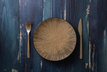 Plate on blue wooden background with utensils