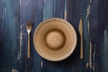 Plate on blue wooden background with utensils
