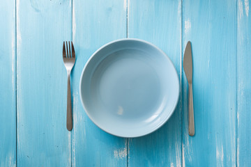 Blue Plate on blue wooden background with utensils