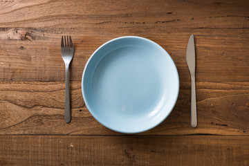 Blue Plate on brown wooden background with utensils