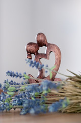 figurine in the form of two men kissing a man and a woman against a background of flowers