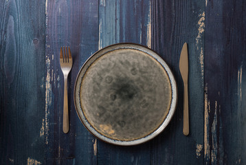 Plate on blue wooden background with utensils