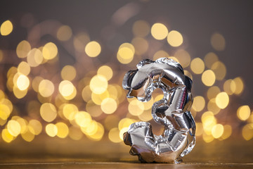 Silver number 3 celebration foil balloon against blurred light background
