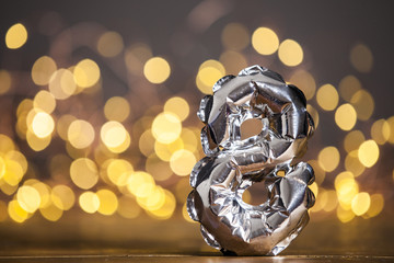 Silver number 8 celebration foil balloon against blurred light background