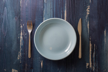 Blue Plate on blue wooden background with utensils