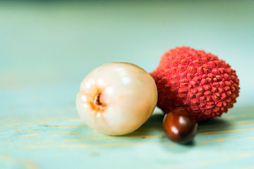 Two lychee fruits and seed wooden background