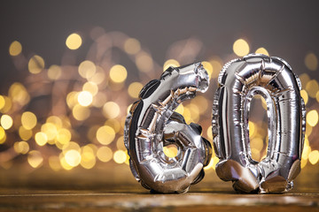 Silver number 60 celebration foil balloon against blurred light background