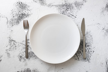 White Plate on white wooden background with utensils