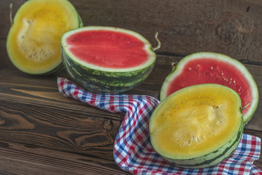 Cut red and yellow watermelons on a wooden box in a vintage wooden background in rustic style, selective focus, toned photo.