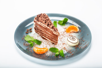 The cake on the plate is decorated with tangerines and chocolate