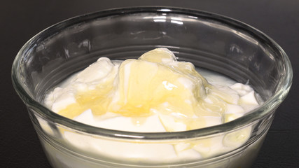 Pouring honey on plain yogurt.