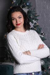 Fototapeta na wymiar Girl with crossed arms on Christmas tree background. Photographie retouchee