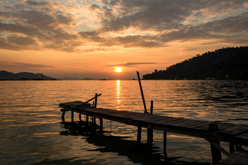 Fototapeta na wymiar tropical sunrise with wooden jetty over island