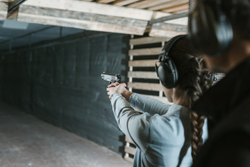 rear view of girl shooting with gun in shooting gallery
