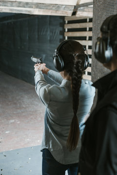 rear view of girl shooting with gun in shooting range