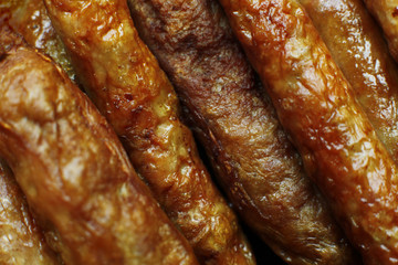 Barbecued meat sausages (bratwurst) close up. Grilled delicious sausages macro shoot.