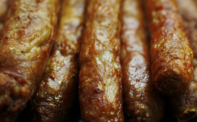 Barbecued meat sausages (bratwurst) close up. Grilled delicious sausages macro shoot.