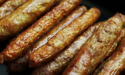 Barbecued meat sausages (bratwurst) close up. Grilled delicious sausages macro shoot.