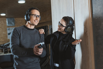 smiling shooting instructor supporting client in shooting gallery