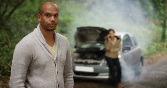 4K Stranded couple with broken down car. Woman talking on phone while man looks fed up. Slow motion.