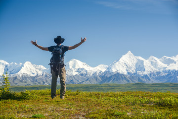man with outstreched arms in front of Alaskan Range, Denali
