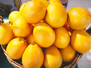 Fruit concept. Many oranges are in a rattan basket for sale in supermarket. Selective focus.