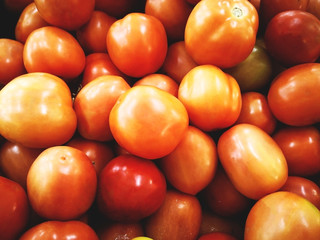 Vegetable concept. Many tomatoes are in a rattan basket for sale in supermarket. Selective focus, full frame and copy space.