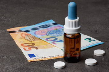 Medizinflasche mit Tabletten und Euro Geldscheinen auf dunklem Hintergrund