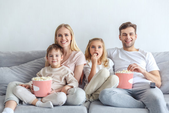 excited young family watching movie on couch at home