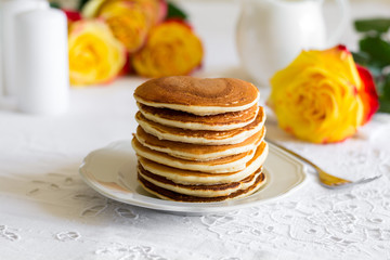 Stack of pancakes with raspberry, red currant, cream and honey on white table cloth